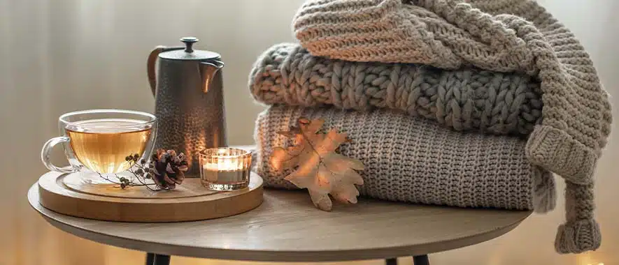 Taza de té y jersey junto a un radiador en invierno